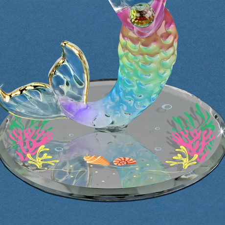 Closeup of mirrored base with shells and seaweed, and rainbow mermaid tail, crystal, gold accents