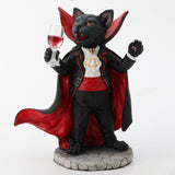 Figurine of black cat in red and black cape, vampire fangs, holding wine glass