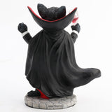 Figurine of black cat in red and black cape, vampire fangs, holding wine glass, shown from the back