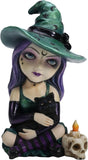 Figurine of witch in green hat, striped purple and black stockings, purple hair holding black cat, next to skull candle