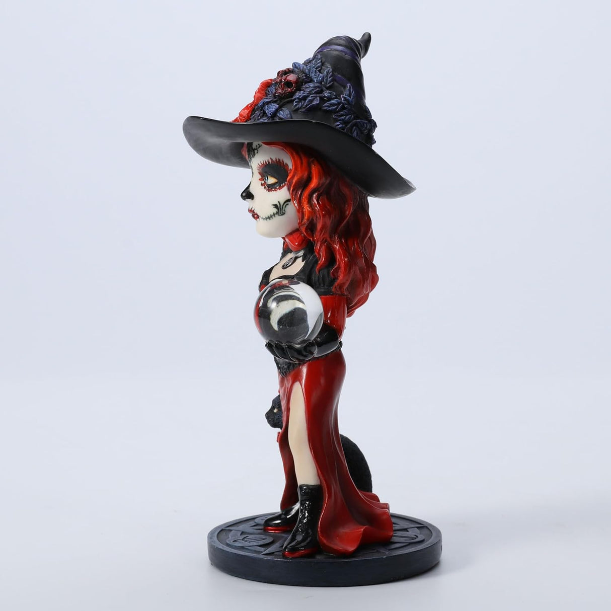 Figurine of witch in red and black with cat and crystal ball, Day of the Dead face paint
