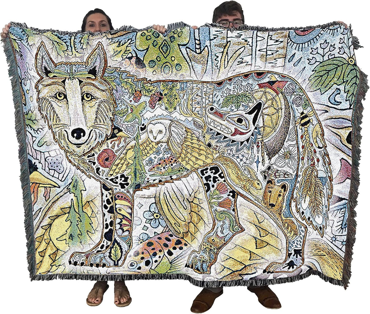 Two people holding a colorful blanket with animal designs.