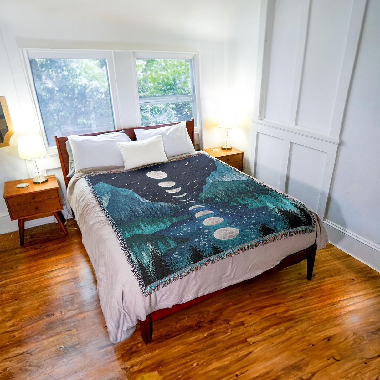 Bedroom with a bed featuring a decorative blanket with moon phases design.