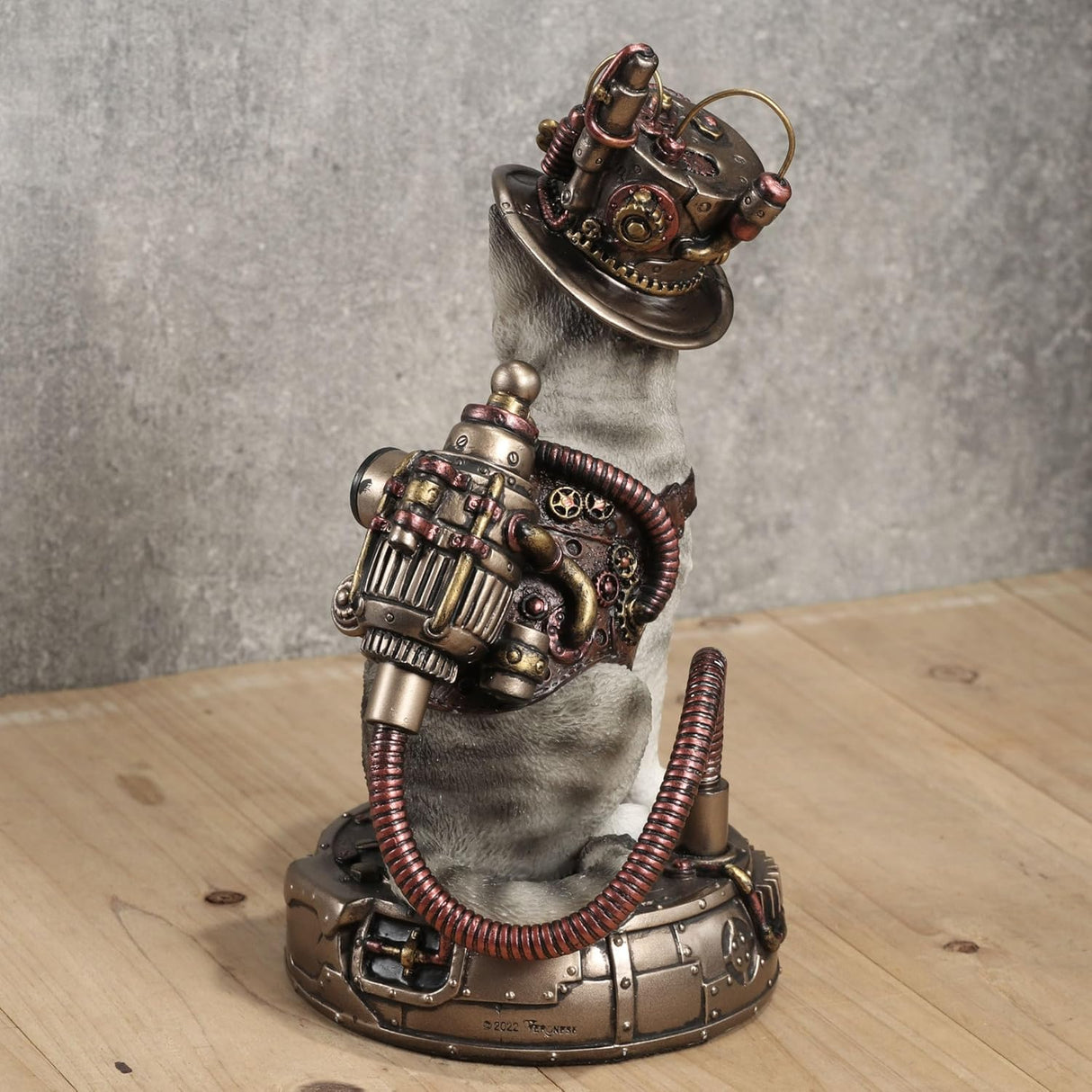 Figurine of pale gray tabby cat with Steampunk hat and gear on a matching base, shown from the back