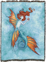 Tapestry blanket showing Mermaid with orange and blue tail gazing at starfish on a textured blue background