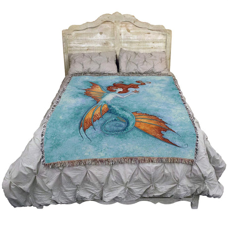 Bed with a decorative blanket featuring a mermaid design