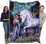 Tapestry blanket with unicorn and maiden in bluebell-filled forest meadow, held up by two adults