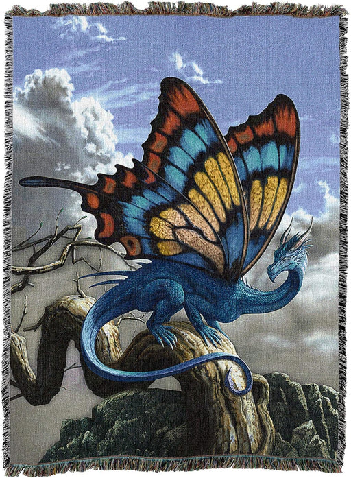 Tapestry blanket of dragon perched on tree on mountain with sky and clouds beyond. Dragon has butterfly wings in red, blue, yellow, with blue scales.