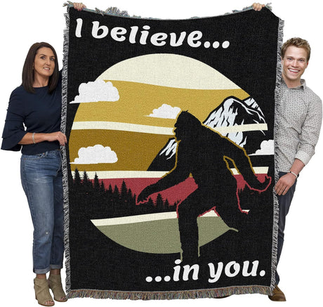 Sasquatch tapestry blanket held by two adults to show large size