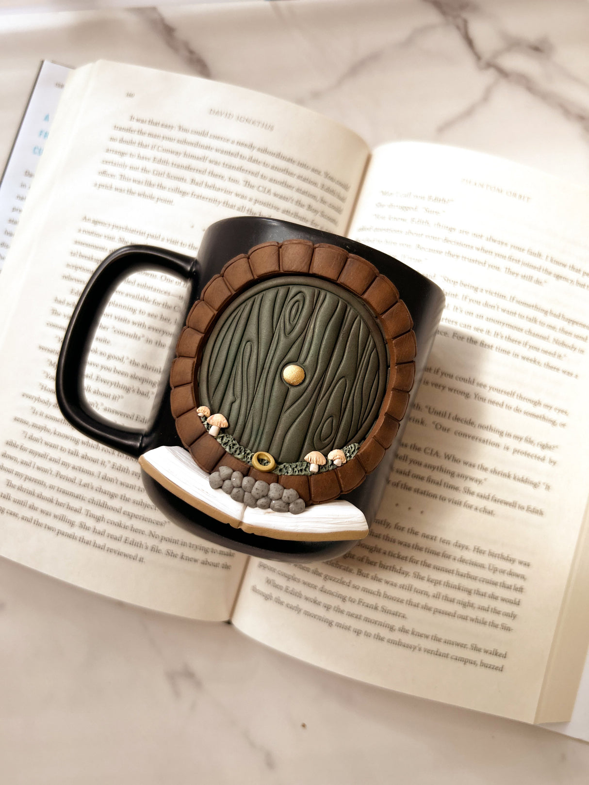 Decorative mug with hobbit door design, displayed on an open book