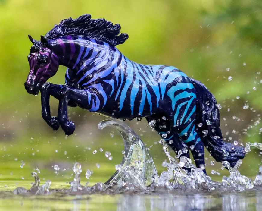 Breyer jumping horse figurine with zebra pattern in gradient purple-blue on black