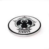 Ceramic coaster, white with black winged cat sitting on skulls with word "Sinner" underneath