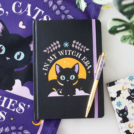 Black notebook with a cat illustration and 'In My Witch Era' text, with pen