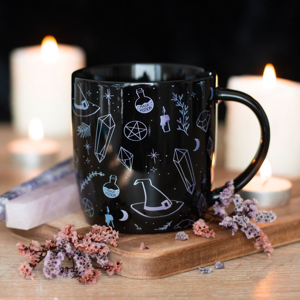 Mug with designs of crystals, witch hats, moons, stars, potion bottles, candles on black background