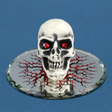 Glass skull figurine with red crystal eyes on a decorated mirrored base