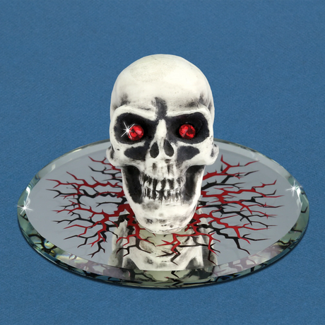 Glass skull figurine with red crystal eyes on a decorated mirrored base