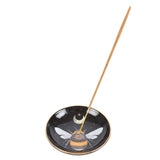 Incense burner dish, round, with bee and moon design, shown with incense