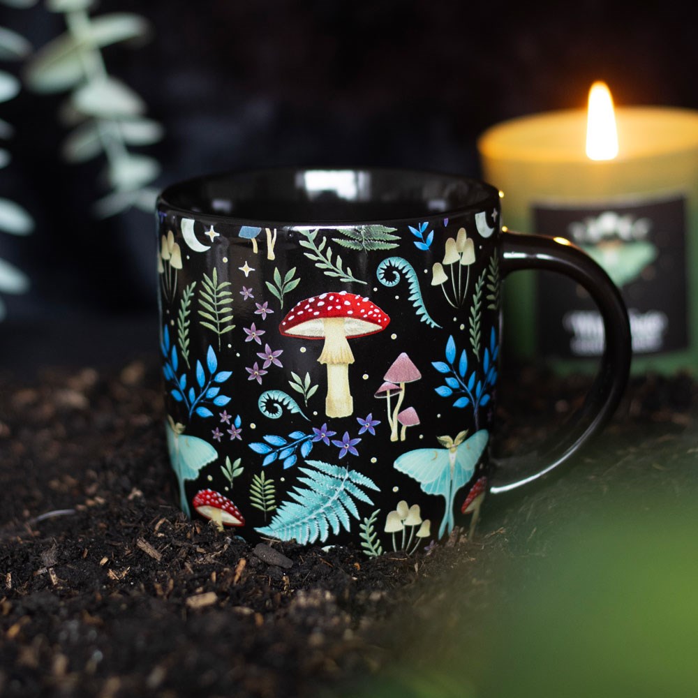 Black ceramic mug with designs of mushrooms, ferns, luna moths