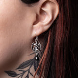 Close-up of an ear wearing a pewter earring with a black teardrop pendant
