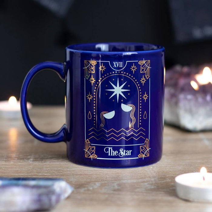 Blue "The Star" tarot card themed mug shown on a table with out of focus crystals and candles