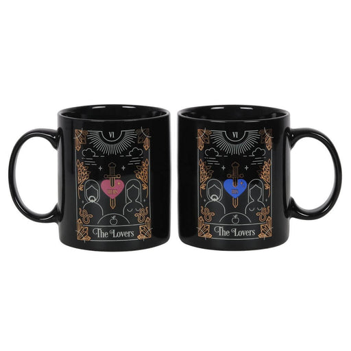 Mug set themed for tarot card "The Lovers". Both mugs are black with white and gold foil design, one has red heart and one has a blue heart with sword through.