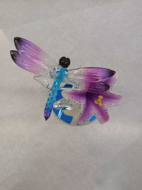 Glass dragonfly perched on a pink and white lily flower with a mirror base