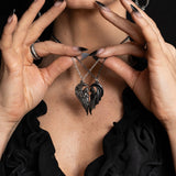 Pair of angel and demon pendants forming a heart shape, shown worn