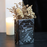 Black vase container with 'Book of Spells' design featuring a raven on a white background, shown with dried flowers