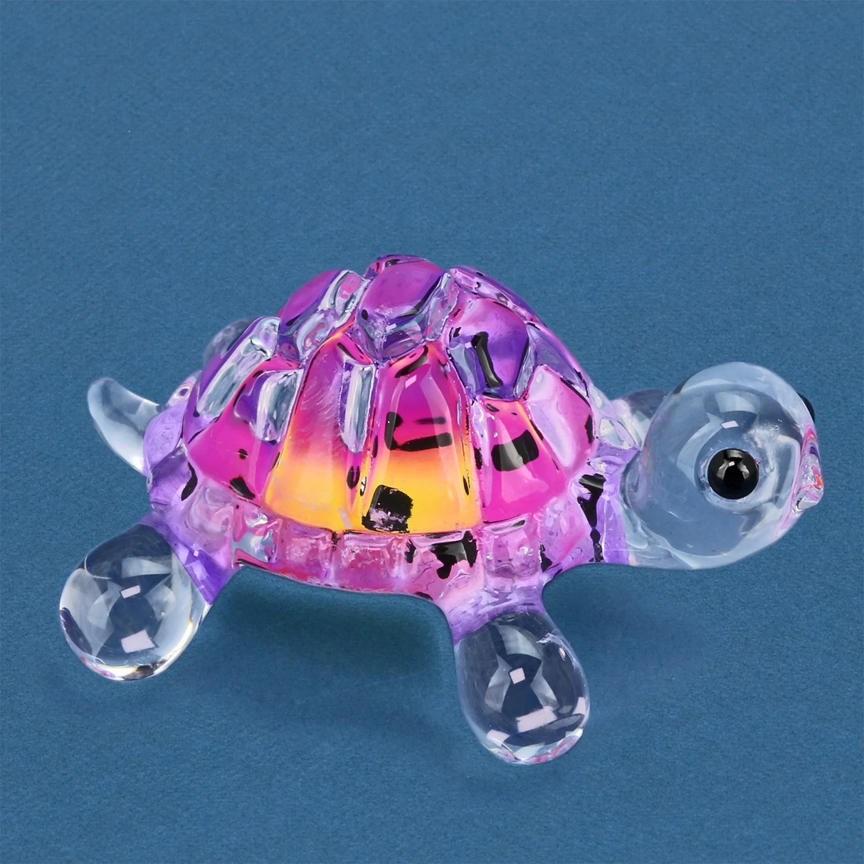Colorful pink and clear glass turtle figurine on a blue background