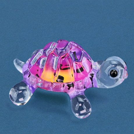 Colorful pink and clear glass turtle figurine on a blue background