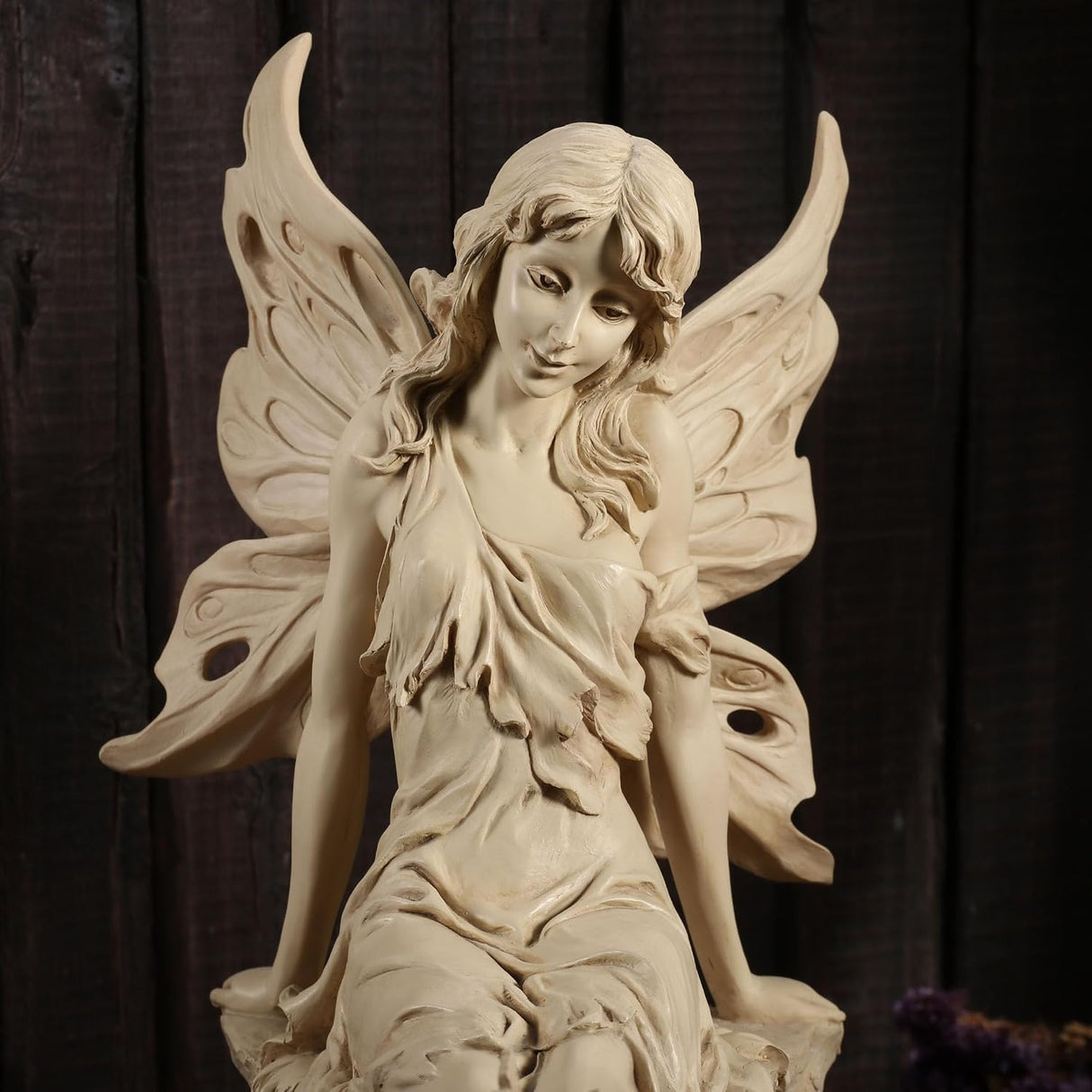 Statue of a fairy with wings sitting on a rock