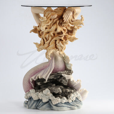 Glass topped mermaid table. Mermaid has blond hair and a pink tail, sitting on waves. Shown from the back