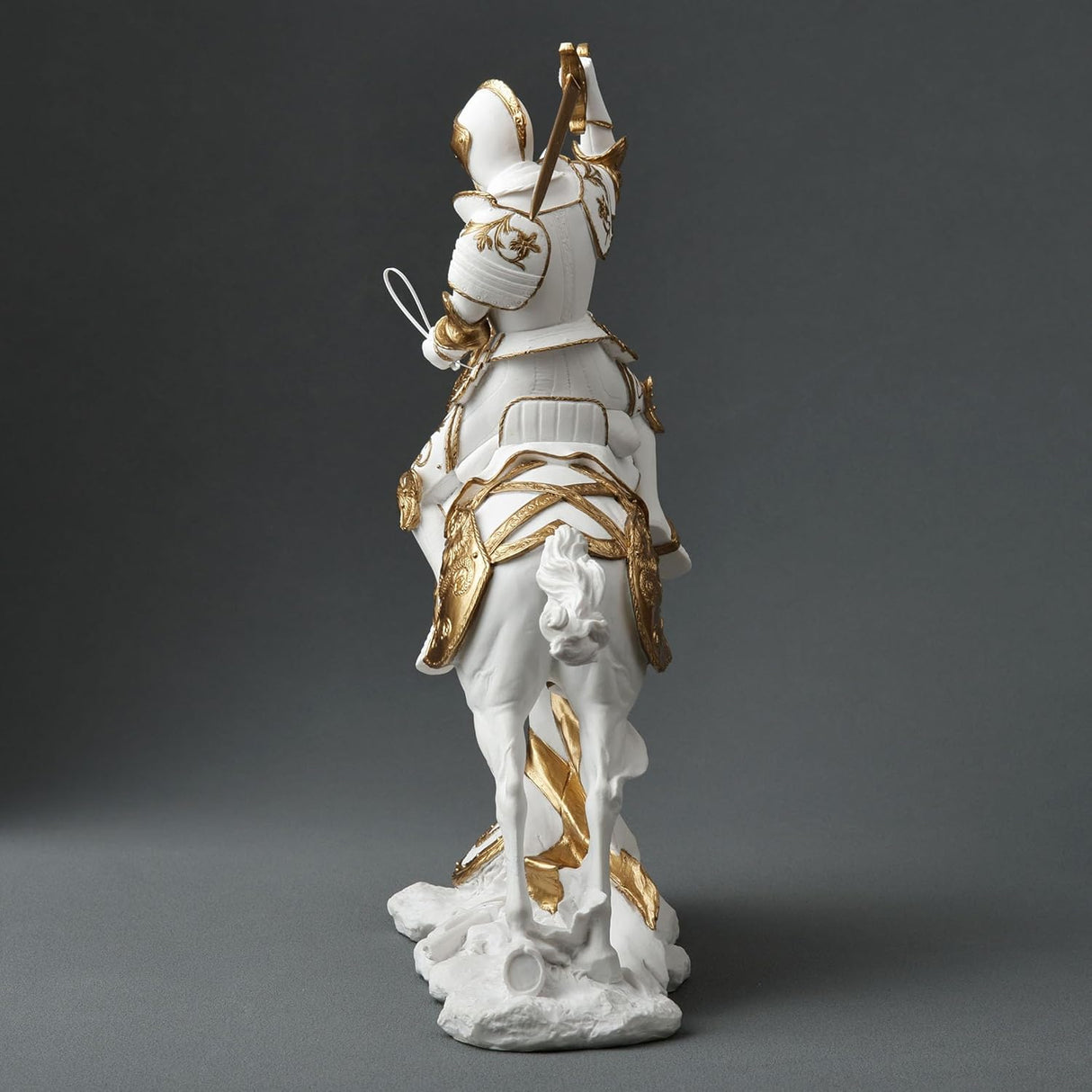 Statue of a knight on horseback with armor and sword, white and gold color scheme. View from the back