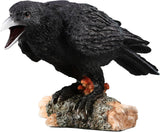 Black crow figurine on a log