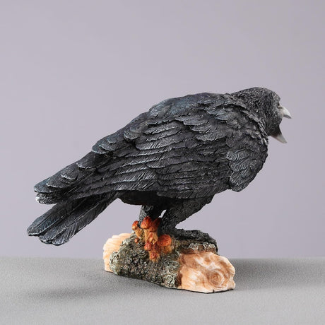 Black crow figurine on a log