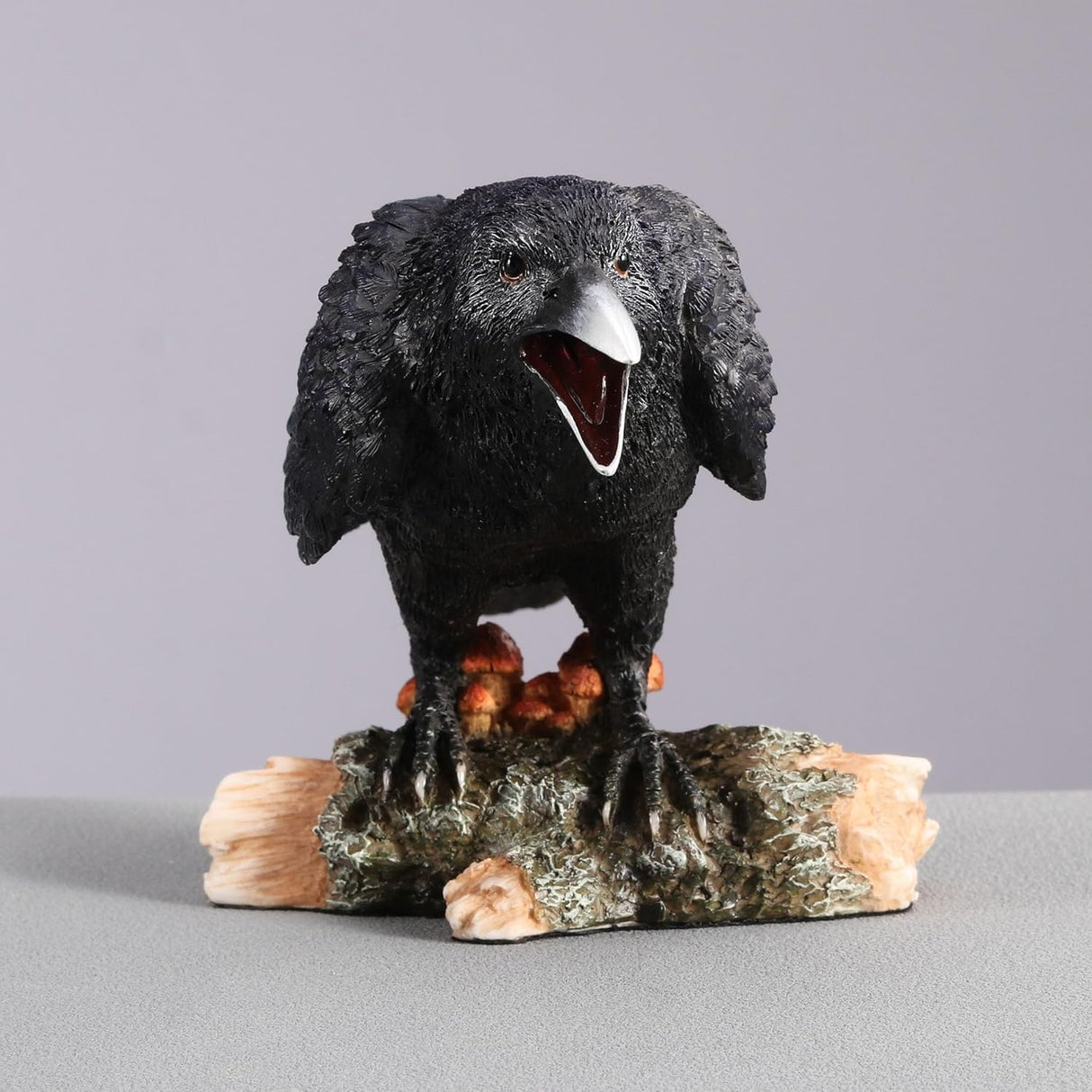 Black crow figurine on a log