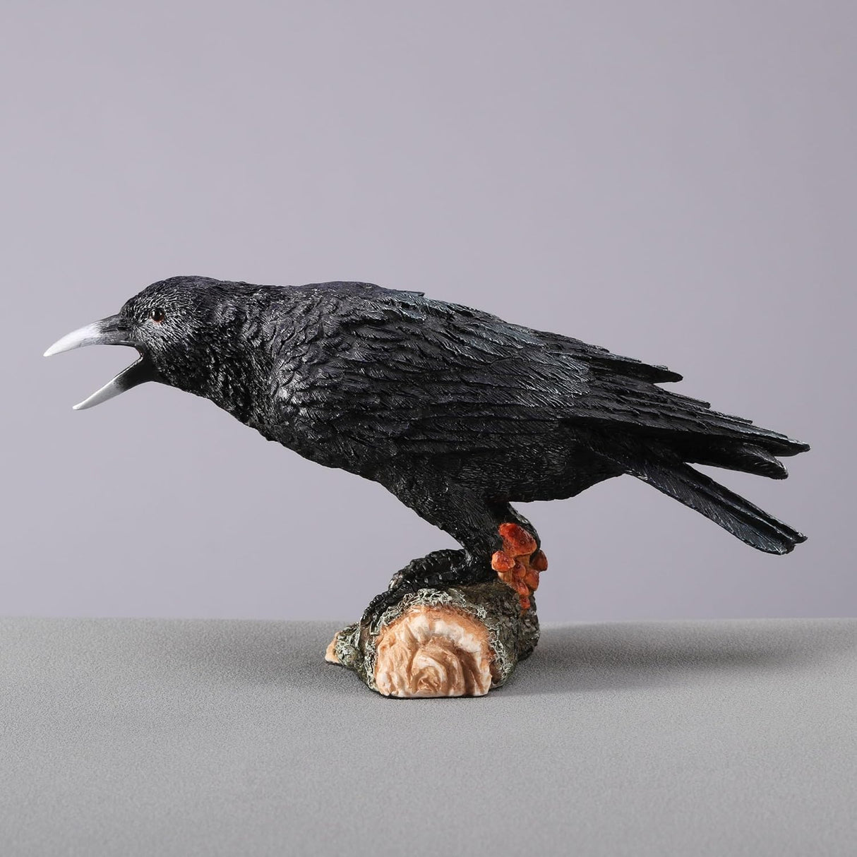Black crow figurine on a log