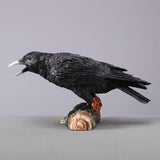 Black crow figurine on a log