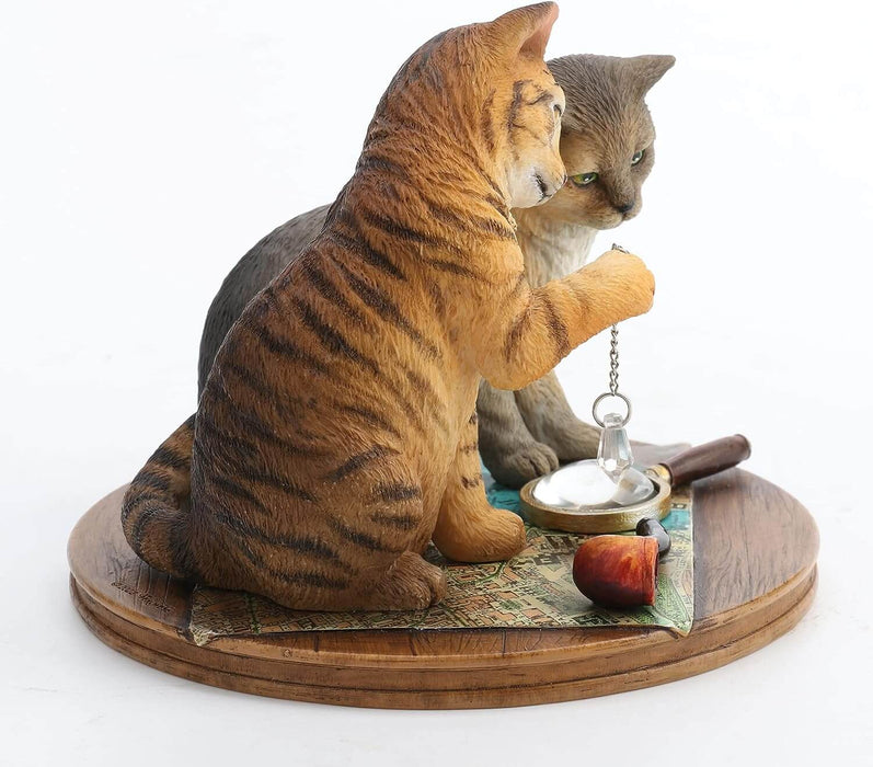 Orange tabby and grey cat contemplate a crystal while sitting on a map with magnifying glass & pipe nearby. Figurine based on artwork of Lisa Parker. shown from the side