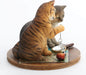 Orange tabby and grey cat contemplate a crystal while sitting on a map with magnifying glass & pipe nearby. Figurine based on artwork of Lisa Parker. shown from the side