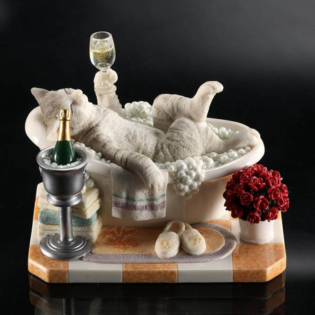 Figurine of a gray striped cat in a bubble bath with champagne, roses, and slippers.