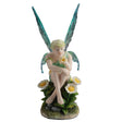 Fairy figurine with green wings sitting among flowers on a white background