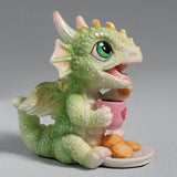 Figurine of a green baby dragon with a pink heart mug and plate of cookies