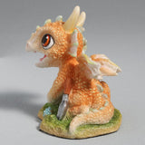 Figurine of a pale gold baby dragon gardening with flowers and a trowel