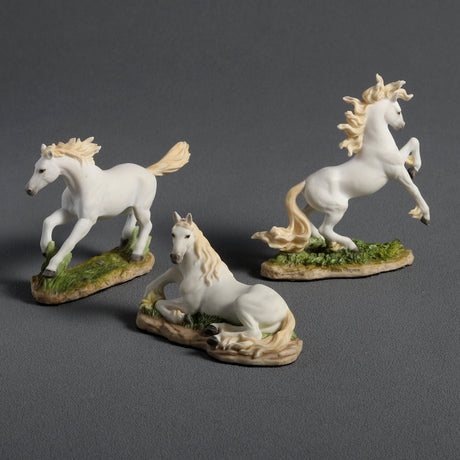 Three white horse figurines on a gray background. Running, prancing, and laying down
