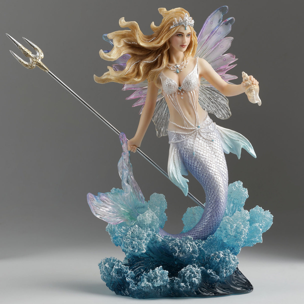 Mermaid fairy figurine with a trident and seashell bursting out of the waves