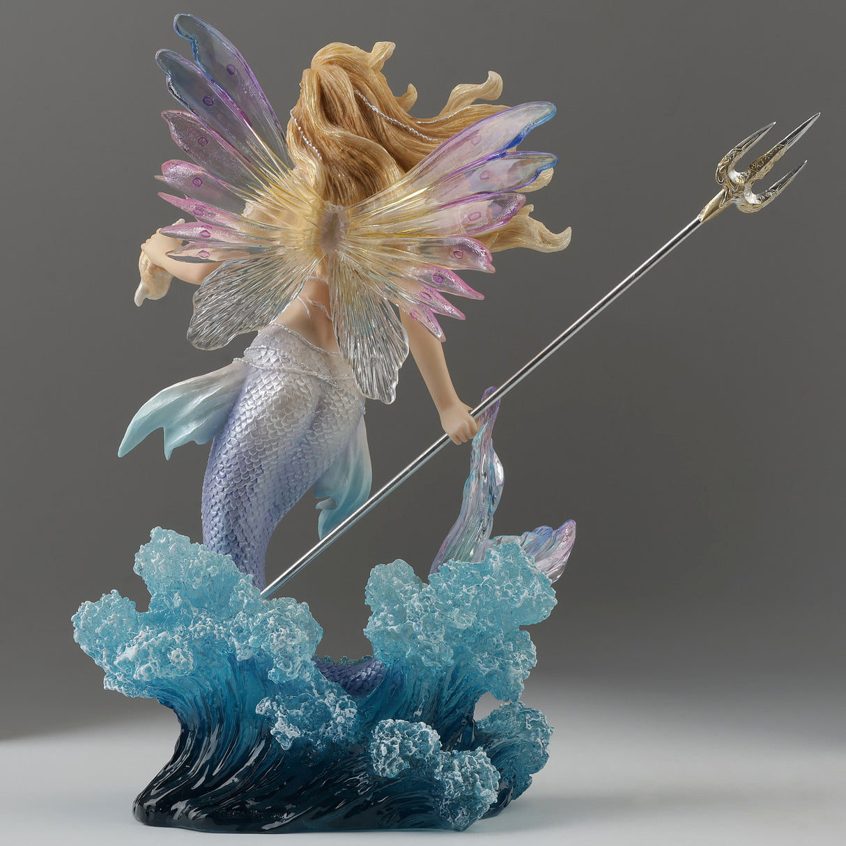Mermaid fairy figurine with a trident and seashell bursting out of the waves, shown from the back