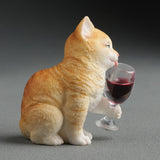 Orange cat figurine holding a wine glass with red wine