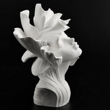 Bronze bust of a woman with flower petals for hair, in white, from the side