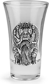A clear glass shot glass featuring a detailed pewter relief of a triple moon goddess figure, Hecate, flanked by two wolves